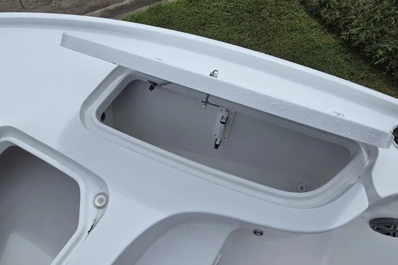 Slide: The Image of 2026 Sea Hunt BX 22 BR boat storage compartment, open lid, white interior, grassy background. - 19