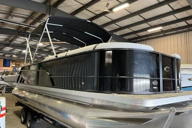 Slide: The Image of 2023 Crest LX 240SLSC pontoon boat in a warehouse, featuring sleek design and black canopy. - 1