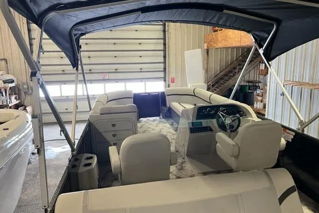 Slide: The Image of 2023 Crest LX 240SLSC pontoon boat interior with seating and steering wheel in a garage. - 6