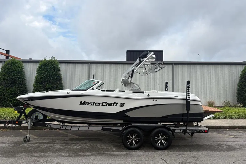 Slide: The Image of 2014 MasterCraft X10 boat on trailer, parked outdoors, with overcast sky background. - 6