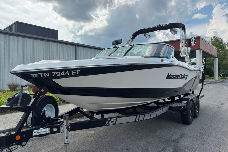 Slide: The Image of 2014 MasterCraft X10 boat on trailer, parked outdoors under cloudy sky. - 7