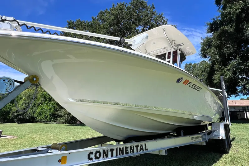 Slide: The Image of 2020 Key West 230 Bay Reef boat on trailer, parked on grass under blue sky. - 15