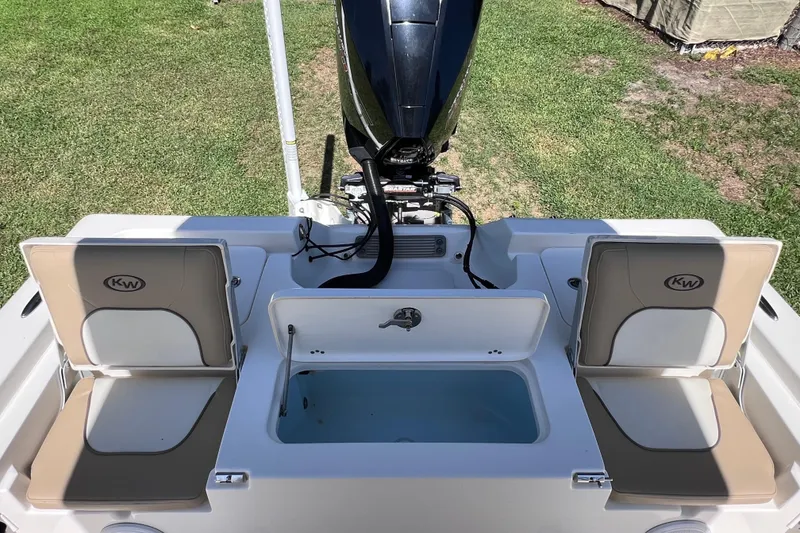 Slide: The Image of 2020 Key West 230 Bay Reef boat interior with seating and motor, on grass. - 27