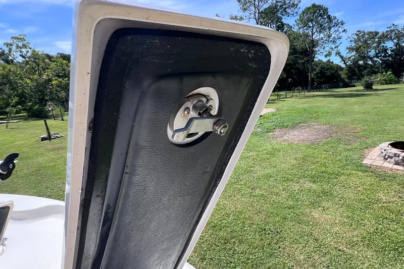 Slide: The Image of 2020 Key West 230 Bay Reef boat hatch open, revealing latch mechanism, grassy background. - 38