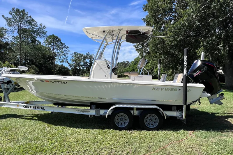 Slide: The Image of 2020 Key West 230 Bay Reef boat on trailer, parked on grass under clear blue sky. - 9