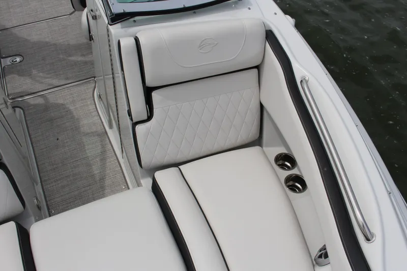 Slide: The Image of 2023 Crownline E235 boat interior with white cushioned seating and stainless steel cup holders. - 11
