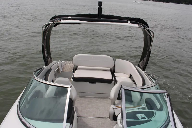 Slide: The Image of 2023 Crownline E235 boat interior with seating, on calm water. - 12