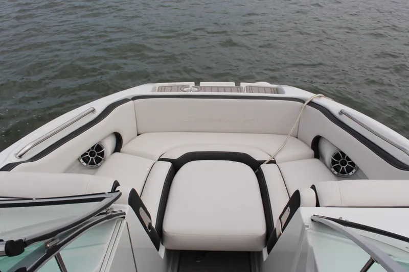Slide: The Image of 2023 Crownline E235 boat interior with plush seating and speakers, on calm water. - 15