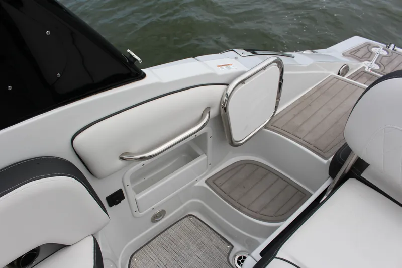 Slide: The Image of 2023 Crownline E235 boat interior with sleek seating and storage, near water. - 20