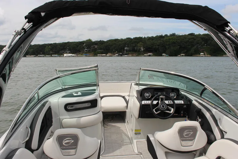 Slide: The Image of 2023 Crownline E235 boat interior with steering wheel, seats, and lake view. - 25