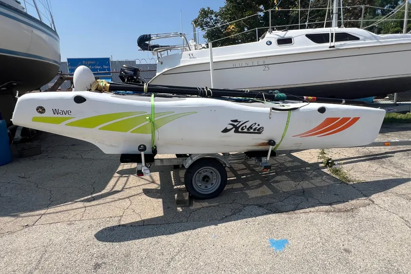 Slide: The Image of 2019 Hobie Cat Wave 13 sailboat on trailer, parked outdoors. - 3