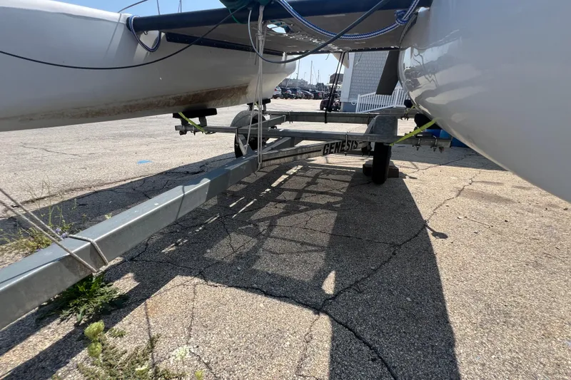 Slide: The Image of 2019 Hobie Cat Wave 13 catamaran on a Genesis trailer, parked on cracked pavement. - 6