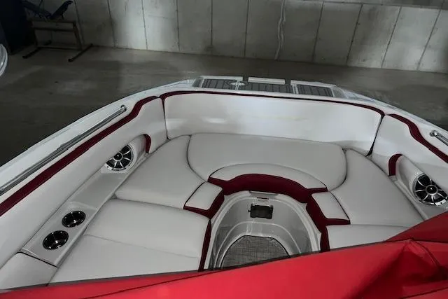 Slide: The Image of 2023 Crownline E255 boat interior with white and red seating, cup holders, and speakers. - 6
