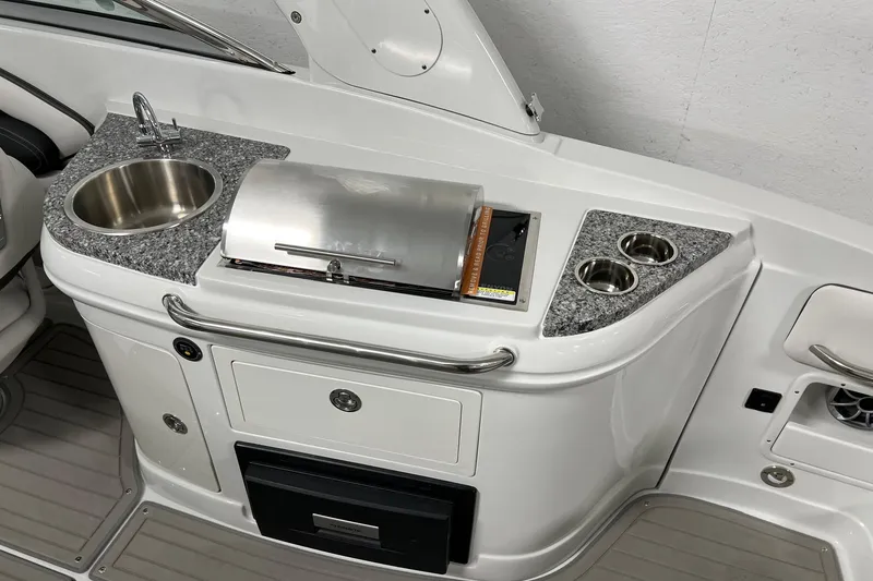 Slide: The Image of 2023 Crownline E285 boat kitchenette with sink, grill, and cup holders. - 4