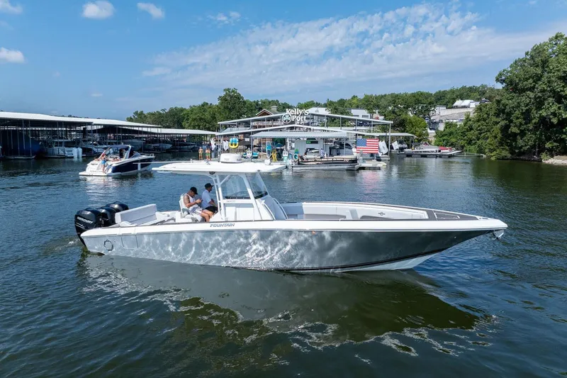Slide: The Image of 2018 Fountain 38 SCX boat cruising on a sunny lake near a marina. - 0