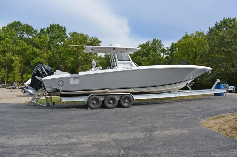Slide: The Image of 2018 Fountain 38 CC boat on trailer, parked outdoors with trees in background. - 10