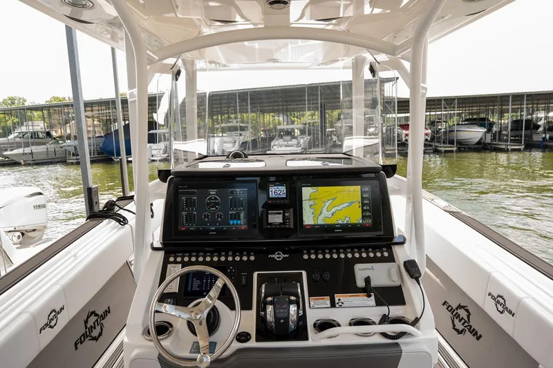 Slide: The Image of 2018 Fountain 38 SCX boat dashboard with navigation screens and controls at a marina. - 16