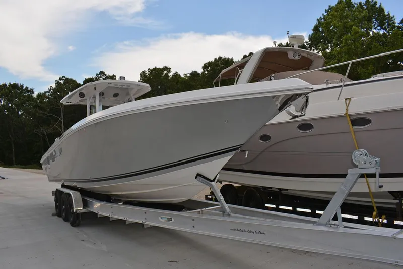 Slide: The Image of 2018 Fountain 38 SCX boat on trailer, parked beside another boat, outdoors. - 30