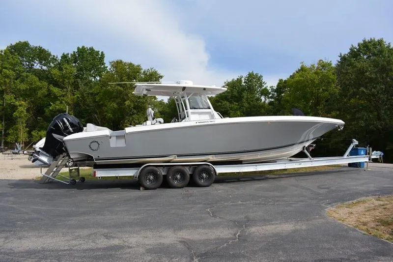 Slide: The Image of 2018 Fountain 38 CC boat on trailer, parked outdoors with trees in background. - 36
