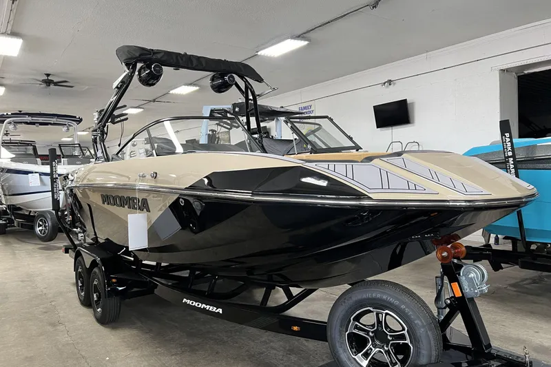 The Image of 2023 Moomba Kaiyen boat on trailer in showroom, featuring sleek design and modern features. - 1