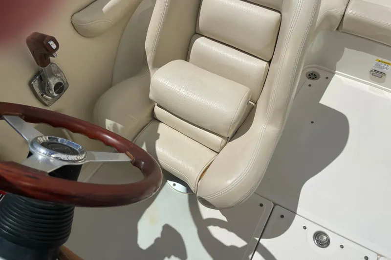 Slide: The Image of 2008 Chris-Craft Launch 25 boat interior with beige seating and wooden steering wheel. - 26