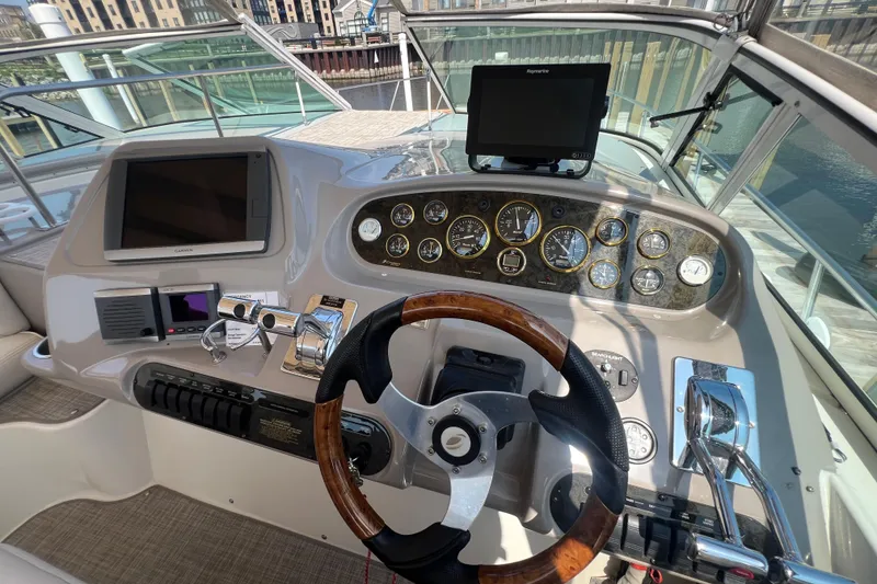 Slide: The Image of 2001 Cruisers Yachts 3672 Express helm with gauges, steering wheel, and navigation screens. - 10