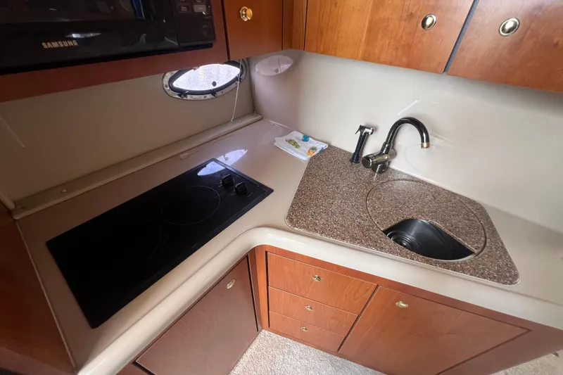 Slide: The Image of 2001 Cruisers Yachts 3672 Express kitchen with stove, sink, and wooden cabinetry. - 22