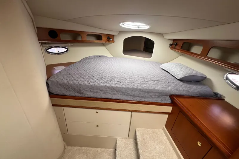 Slide: The Image of 2001 Cruisers Yachts 3672 Express cabin with bed, wooden cabinets, and porthole windows. - 27