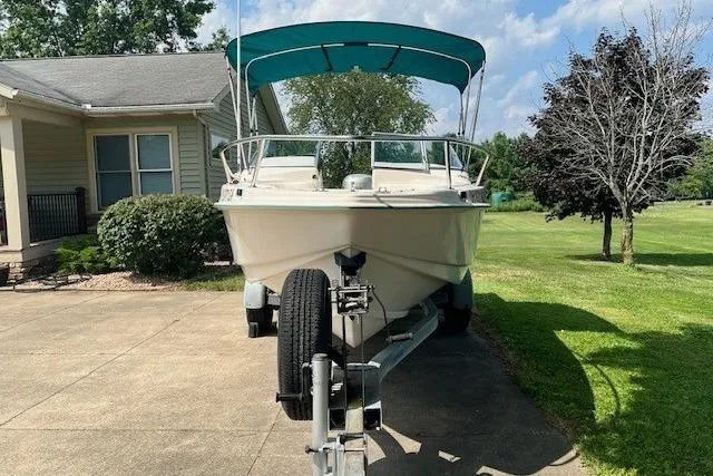 Slide: The Image of 1996 Scout 202 Dorado boat on trailer with teal canopy, parked in driveway. - 4