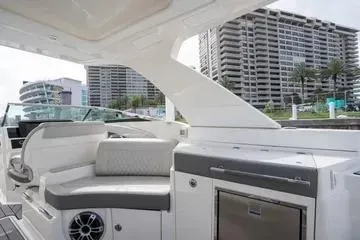 Slide: The Image of 2023 Sea Ray SLX 350 Outboard interior with modern seating and amenities, docked near high-rise buildings. - 12