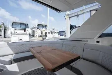 Slide: The Image of 2023 Sea Ray SLX 350 Outboard interior with seating and table, docked at marina. - 15