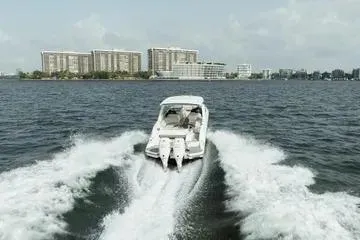 Slide: The Image of 2023 Sea Ray SLX 350 Outboard cruising on water with cityscape in background. - 2