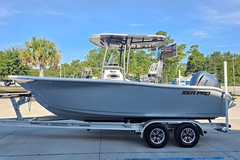 Slide: The Image of 2025 Sea Pro 222 Center Console boat on trailer, parked outdoors with trees in background. - 6