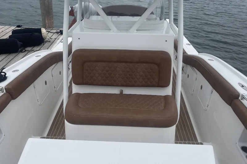 Slide: The Image of 2016 Buddy Davis 28 Center Console boat with brown cushioned seating, docked by the water. - 12