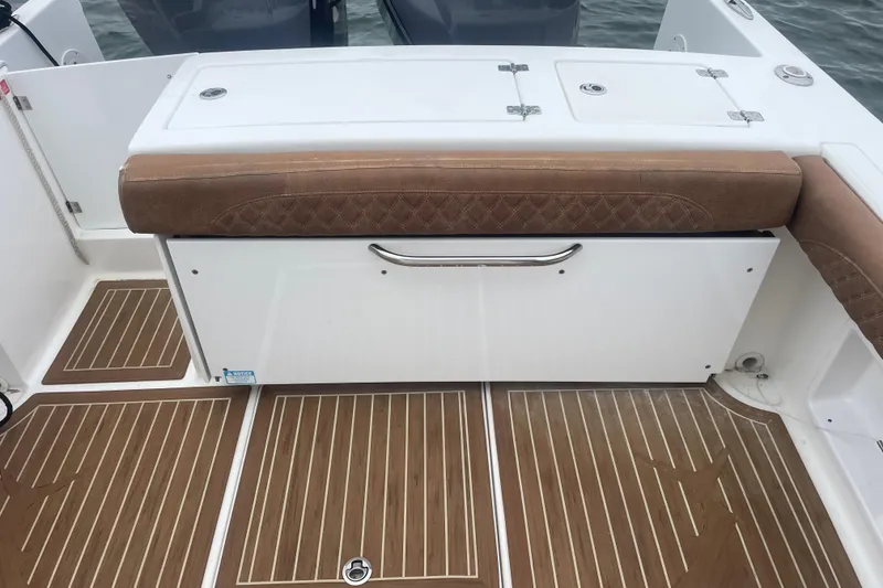 Slide: The Image of 2016 Buddy Davis 28 Center Console boat interior with cushioned seating and wood-patterned flooring. - 2