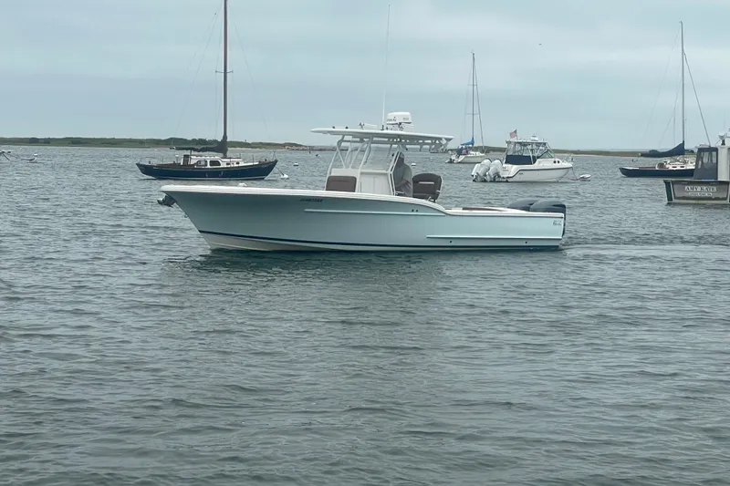 Slide: The Image of 2016 Buddy Davis 28 Center Console boat on calm water with other vessels nearby. - 30