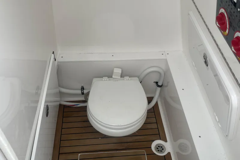 Slide: The Image of 2016 Buddy Davis 28 Center Console boat bathroom with wooden flooring and white toilet. - 9