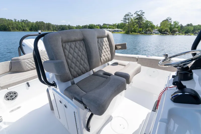 Slide: The Image of 2026 Sea Hunt Ultra 255 SE boat interior with plush seating and steering wheel on a serene lake. - 10