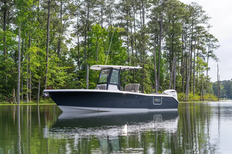 Slide: The Image of 2026 Sea Hunt Ultra 255 SE boat on a serene lake surrounded by trees. - 11