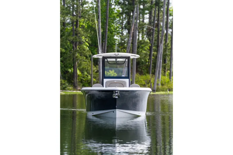 Slide: The Image of 2026 Sea Hunt Ultra 255 SE boat on calm water, surrounded by lush trees. - 15