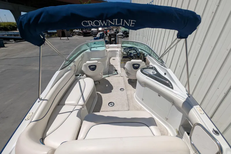 Slide: The Image of 2006 Crownline 240 EX boat interior with seating and canopy, docked outdoors. - 14
