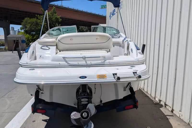 Slide: The Image of 2006 Crownline 240 EX boat, rear view, parked near a building under a bridge. - 24