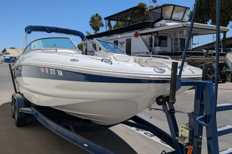 Slide: The Image of 2006 Crownline 240 EX boat on trailer, parked near a marina with other boats. - 3