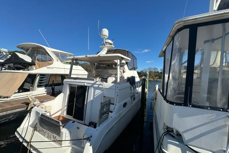 Slide: The Image of 1999 Silverton 442 Cockpit Motor Yacht docked between other boats under clear blue sky. - 10