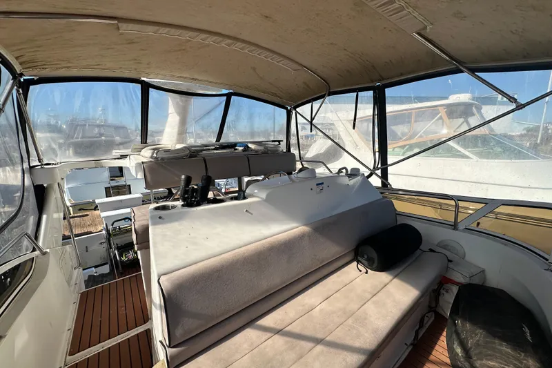 Slide: The Image of 1999 Silverton 442 Cockpit Motor Yacht interior with seating and helm, docked at marina. - 15
