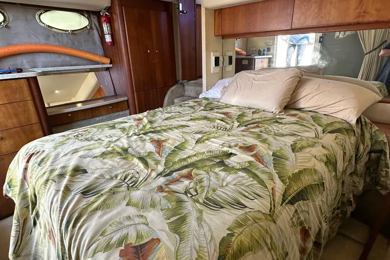 Slide: The Image of 1999 Silverton 442 Cockpit Motor Yacht bedroom with tropical bedding and wooden cabinetry. - 24