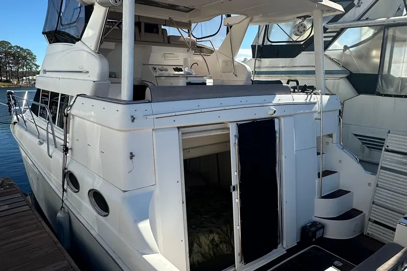 Slide: The Image of 1999 Silverton 442 Cockpit Motor Yacht docked, showcasing rear entry and upper deck. - 31