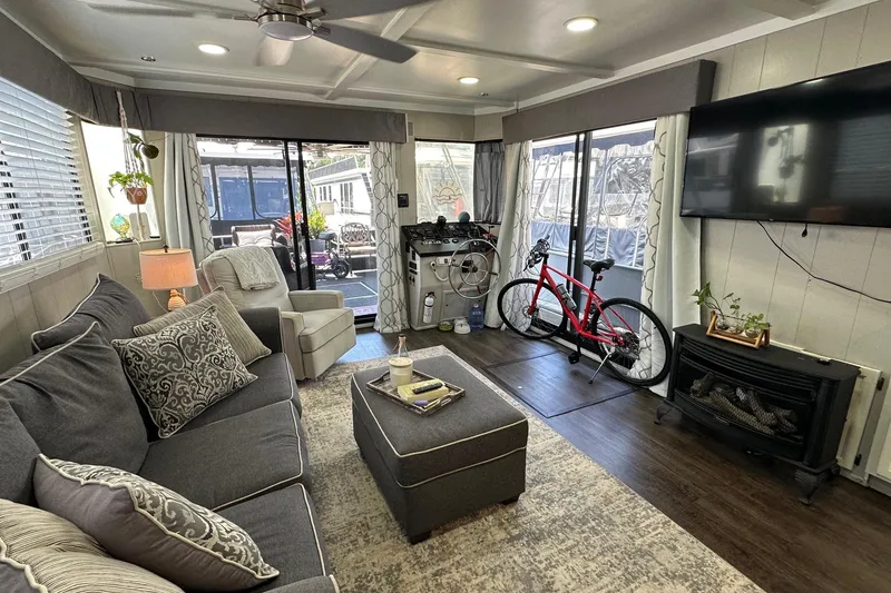 Slide: The Image of Cozy Sumerset 14x65 houseboat interior with modern decor, bicycle, and outdoor view, 1990 model. - 3