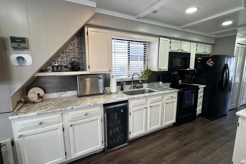 Slide: The Image of Modern kitchen in a 1990 Sumerset 14x65 houseboat with white cabinets and black appliances. - 4