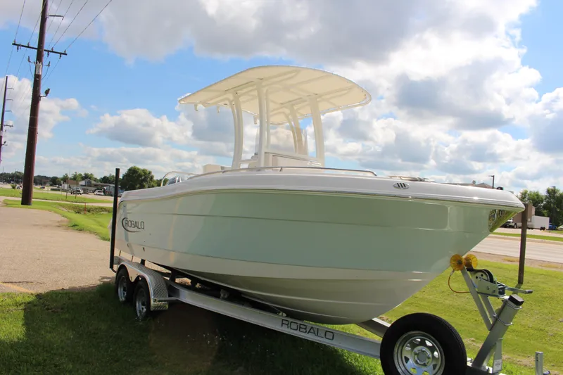 Slide: The Image of 2023 Robalo R222 Center Console boat on trailer under cloudy sky. - 2